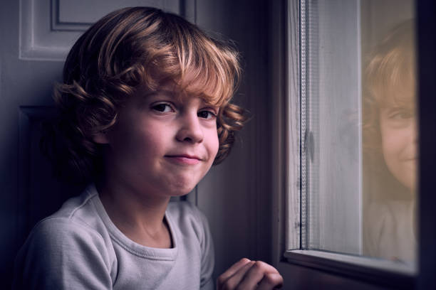 istock Adorable little boy smiling at camera near window 1989747565