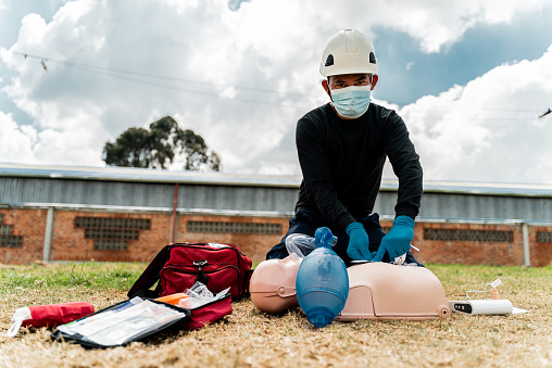 Portrait of a paramedic practicing on a CPR dummy outdoors
