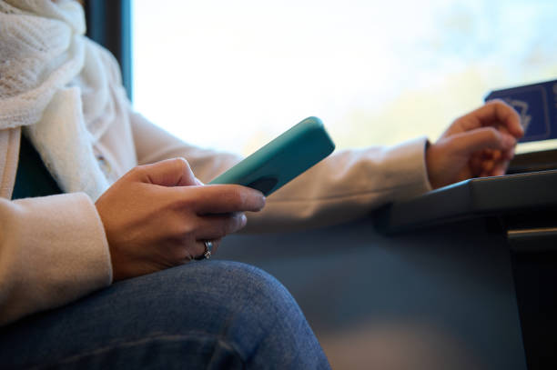 istock Close-up female hand holding smartphone, checking mobile app, planning route while travelling by comfortable city train 1989759951