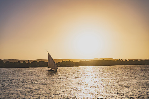 Timeless scene of sunset on the river Nile as boats sails backlit by the setting sun