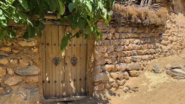 wonderful scenic shot from old traditional house wooden door stone wall tree shade in rural village countryside in Iran Esfahan remote outdoor adventure travel to visit local people life doorknob