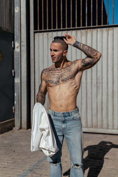 istock Handsome shirtless man with tattoos posing against a building 1989813836