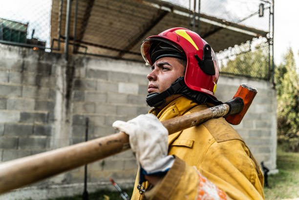Young fireman holding a sledgehammer outdoors