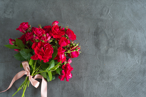 Banner no face a woman in a red dress holds a bouquet of red roses on a gray background place for text, mockup, place for design. Concept: back for the site, layers, birthday, womens day, mothers