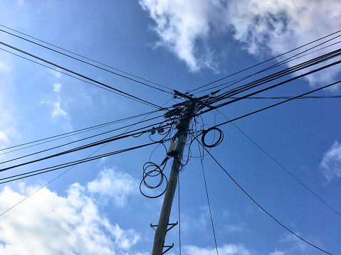 Horizontal Photo of a Messy Electricity, TV, Phone Pylon Cables Over Blue Sky Background