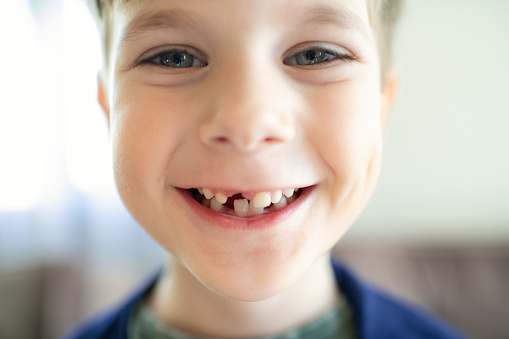 Portrait of smiling little boy, pupil in white shirt showing gesture of positivity against blue studio background. Concept of childhood, education, school, kid emotions, ad