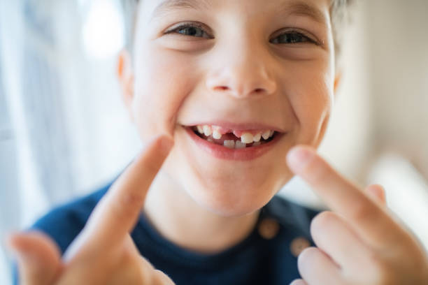 Cute little boy smiling with a milky tooth gap Portrait of a happy child showing hole with missed baby tooth baby teeth stock pictures, royalty-free photos & images