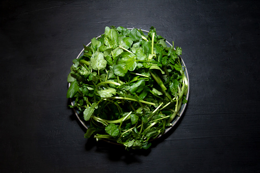 Clean watercress leaves for salad on black background