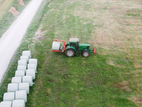 Aerial view of a tractor wrapping a hay bale