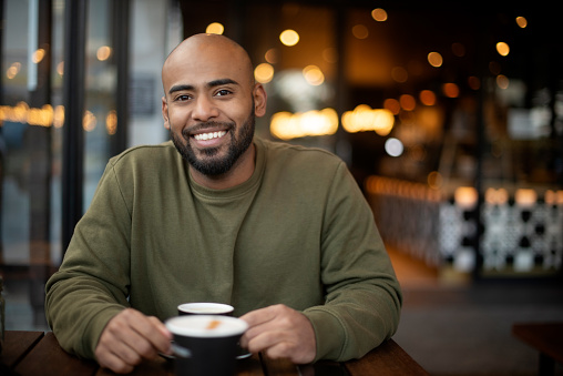 Smile, coffee and portrait of man in cafe with positive, good and confident attitude for caffeine. Pride, excited and happy young male person drinking cappuccino, espresso or latte in restaurant.