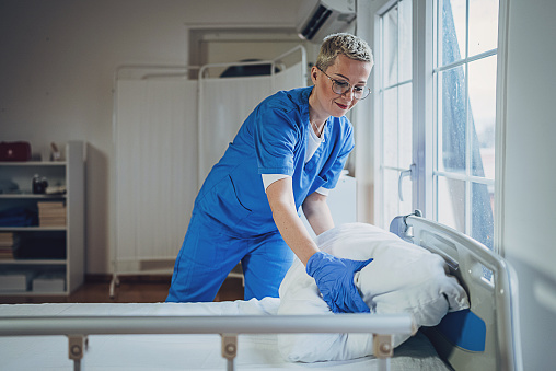 Female nurse making bed at the hospital ward.