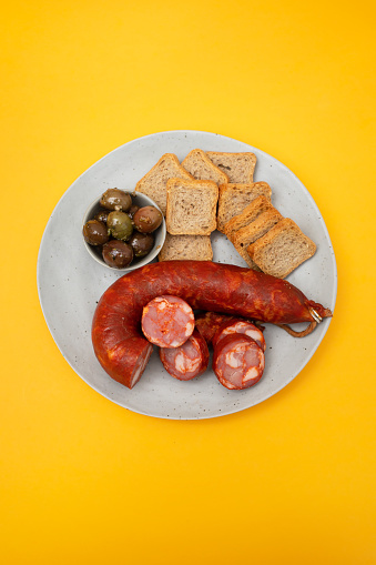 typical portuguese smoked sausage chourico with olives and toasts