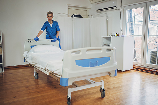 Female nurse arranging bed at the hospital ward.