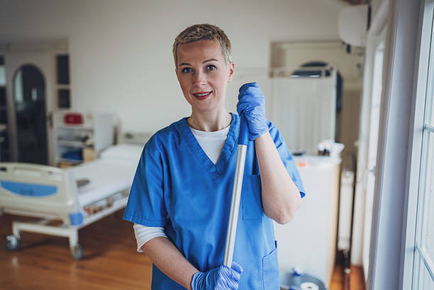 Adult cleaner maid woman with mop and uniform cleaning corridor pass floor of pharmacy industry factory or clinic