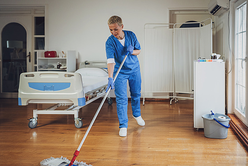Female hygiene worker mopping floor at the hospital ward.
