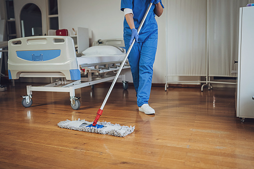 Female hygiene worker mopping floor at the hospital ward.