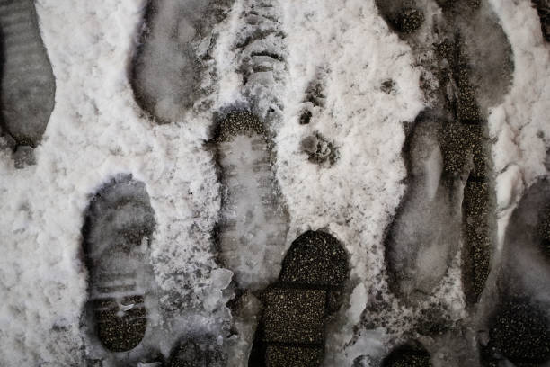 A sidewalk with many footprints in the snow