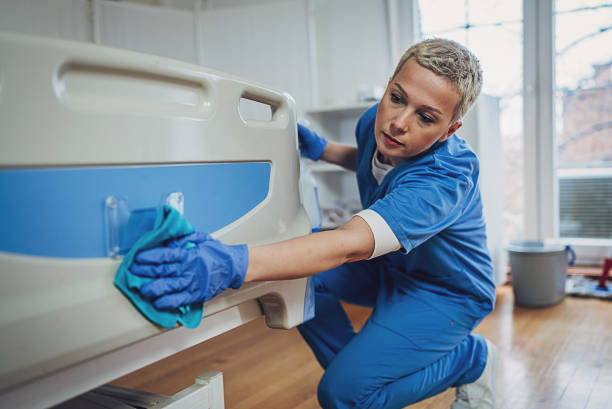 Female nurse cleaning the bed after patients in hospital ward.