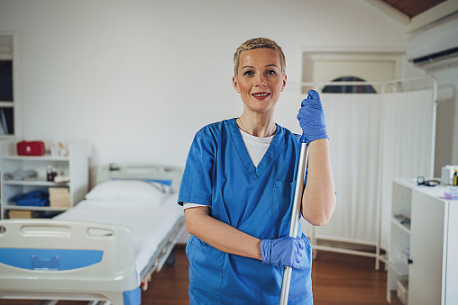 Portrait of a female hygiene worker with a mop at the hospital ward.