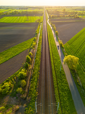 An aerial view of train tracks in a green field on a sunny day