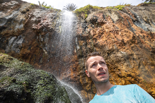 Portrait of man standing under waterfall in Tenerife, Canary Island, Spain.
