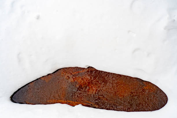 Background with a frozen river surrounded by snow with empty space for text. A natural stream of red color in an iron-rich area.