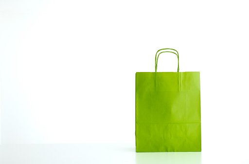 Empty bright apple green paper shopping or gift bag, isolated on white. No people.
