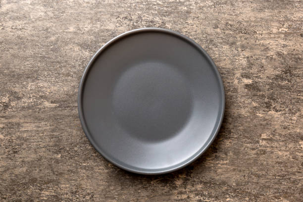 istock Top view of black plate on cement background. Empty space for your design 1989981842