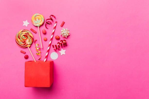 istock gift box in corner full of assorted traditional candies falling out on colored background with copy space. Happy Holidays sale concept 1989982438
