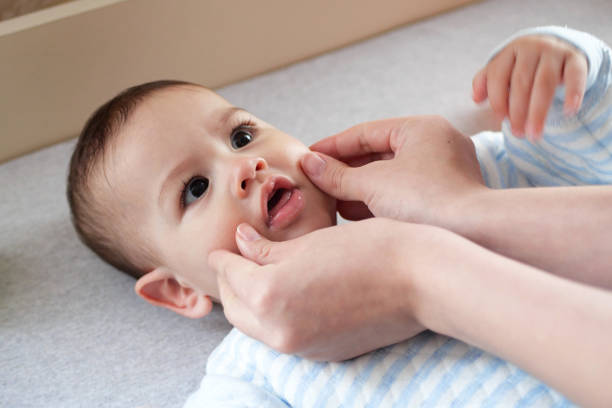istock Happy Baby boy lying, mother's hand pressing her cheeks 1989982477