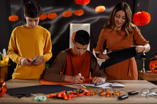 mãe e dois filhos fazendo decorações de papel para halloween - 12 15 months - fotografias e filmes do acervo