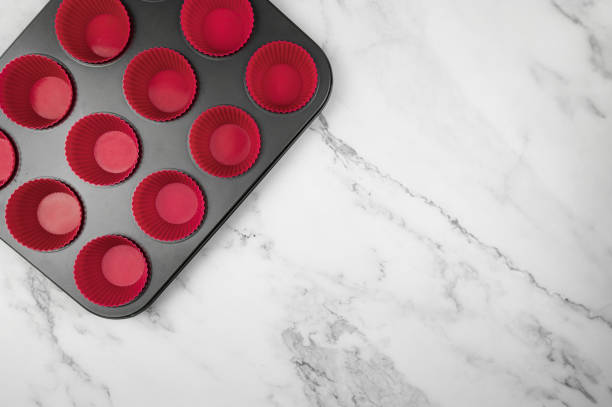 istock Top view of cupcake pan and silicone cases on white marble background. 1989996214