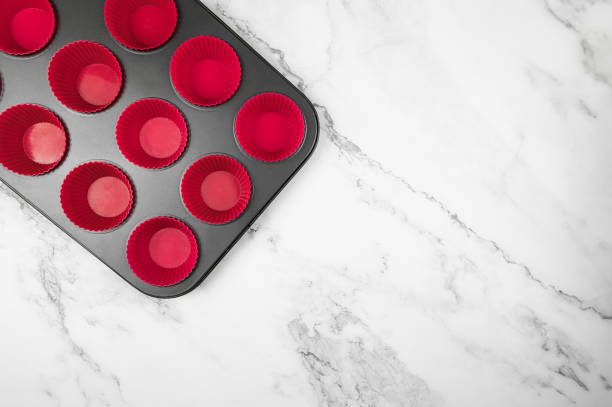 istock Top view of cupcake pan and silicone cases on white marble background. 1989996555