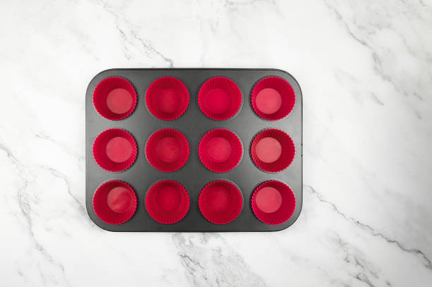istock Top view of cupcake pan and silicone cases on white marble background. 1989996581