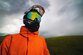 rider in a helmet and goggles, full protective equipment on an MTB bicycle or motorcycle stands on a rock against the backdrop of hills and low clouds