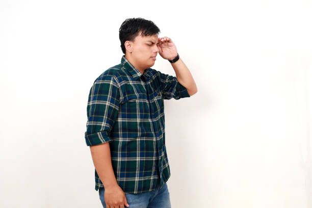 istock Confused young handsome asian man standing while suffering from headache. Isolated on white 1990008114