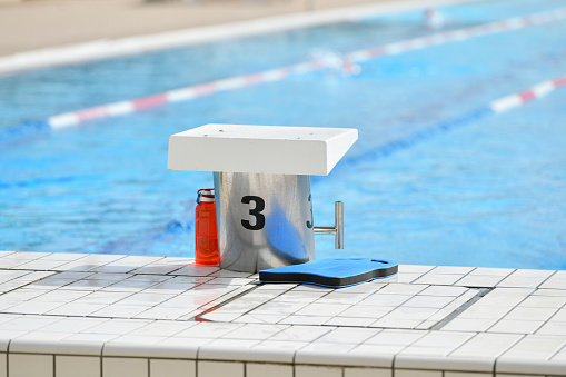 Young woman in goggles swims with a board in the pool