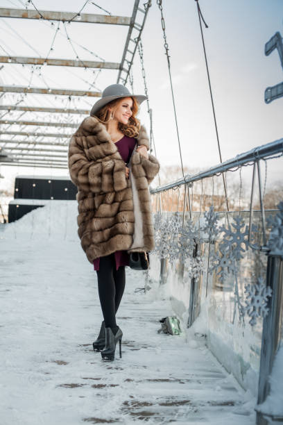 mujer morena feliz con vestido rojo y abrigo de invierno de visón de piel - russian culture fashion model hat sensuality fotografías e imágenes de stock