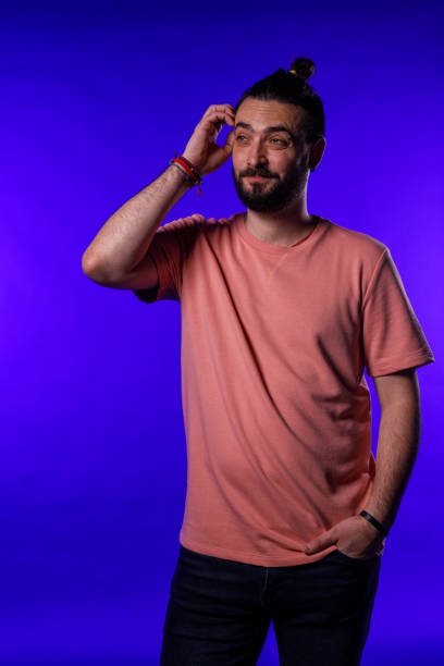istock Confused hipster contemplating solutions against blue background 1990038678