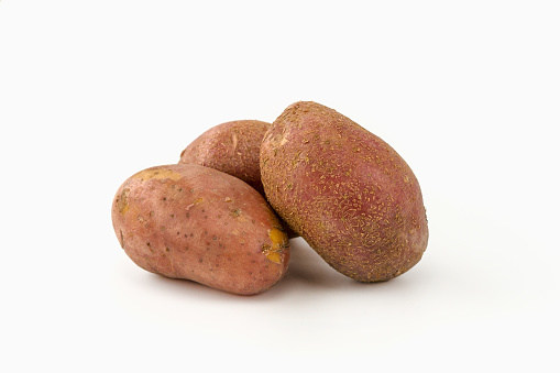 Three red-brown old potatoes on a white isolated background.
