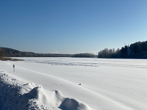 beautiful winter landscape. Frozen lake covered with snow frosty sunny day, blue sky