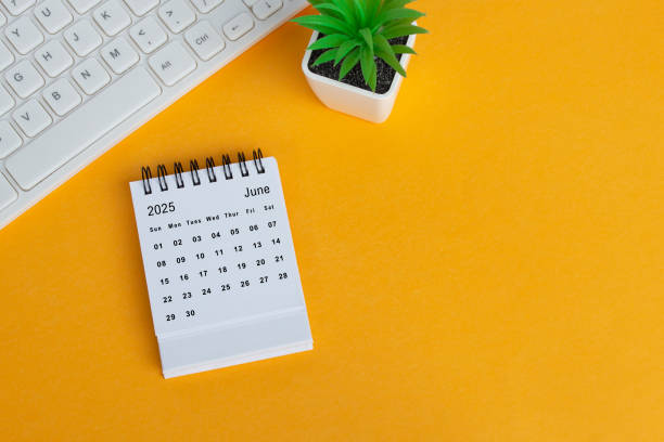 istock June 2025 desk calendar on yellow background. Directly above. Flat lay. 1990105215