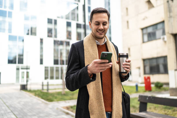 istock Smiling businessman using phone outdoors 1990135393