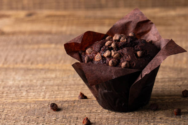 istock Chocolate dark muffin with chocolate chips and drops on a wooden table 1990143627