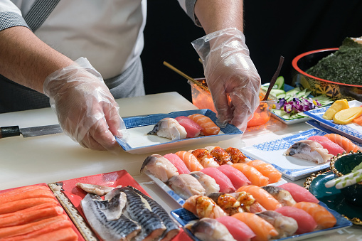 A skilled chef prepare a variety of sushi on a table. Mixing flavor, texture, and color, the chef creates culinary art. Each sushi is a precise masterpiece, showcasing their expertise and dedication.