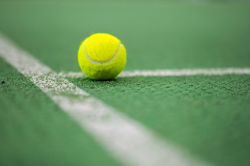 Close-up of tennis ball in green tennis field.