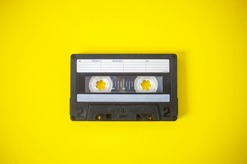 Vintage audio cassette showcased against a yellow backdrop, capturing the nostalgic and vibrant essence of the analog music era. Perfect for projects celebrating the past.