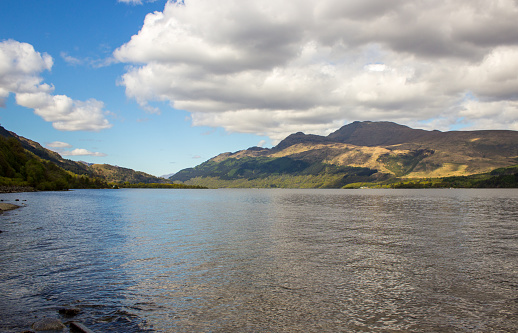 View over Loch Lommond, with the rugged peak of Ben Lommond in shadow, rising in the background, in the Scottish Highlands. Loch Lomond is the largest of all the Scottish lochs and is often considered to form the boundary between the Scottish Highlands and Lowlands.