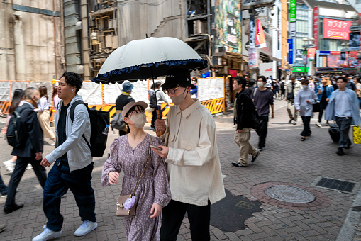 Tokyo, Japan, May 3rd - Couple walking with parasul against the sunshine in a back street in Shibuya district