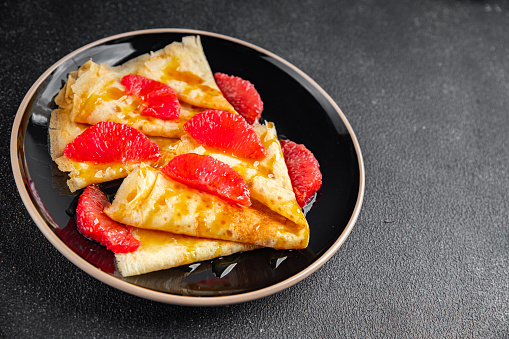 Crepes grapefruit citrus pancakes tasty fresh healthy eating cooking appetizer meal food snack on the table copy space food background rustic top view